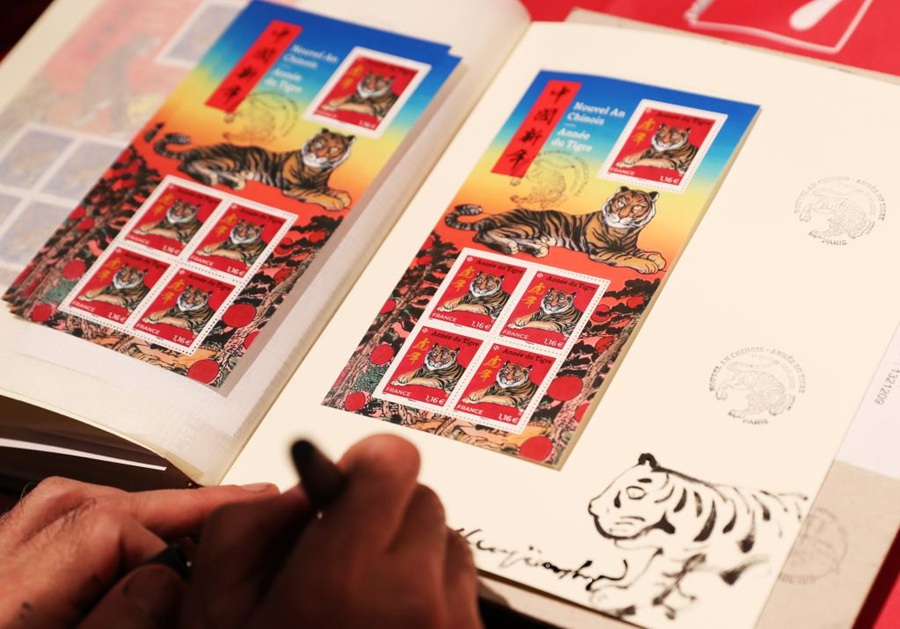 L'artista cinese con sede a Parigi Chen Jianghong firma i francobolli commemorativi dell'Anno della Tigre da lui disegnati durante la cerimonia di emissione a Parigi, Francia. (22 gennaio 2022 - Xinhua/Gao Jing)