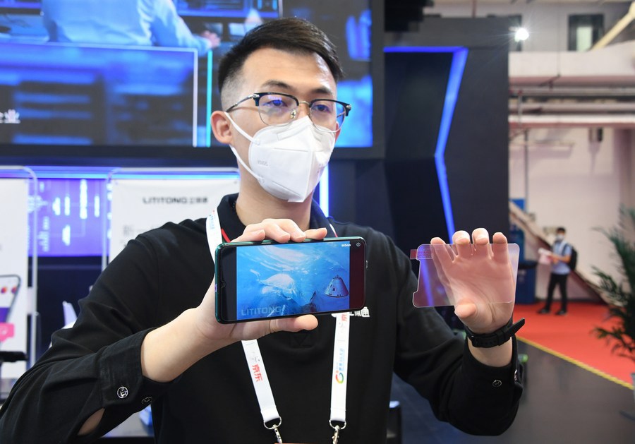 Un membro dello staff mostra una pellicola per lo schermo del telefono cellulare in grado di generare una visione 3D con applicazioni telefoniche, durante la Convenzione mondiale 5G del 2021 a Beijing, capitale della Cina. (31 agosto 2021-Xinhua/Ren Chao)