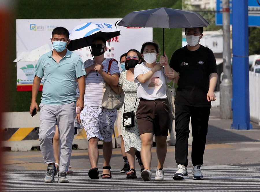La gente cammina per strada nel mezzo dell'ondata di caldo nel distretto Minhang di Shanghai, Cina orientale. (10 luglio 2022-Xinhua/Liu Ying)