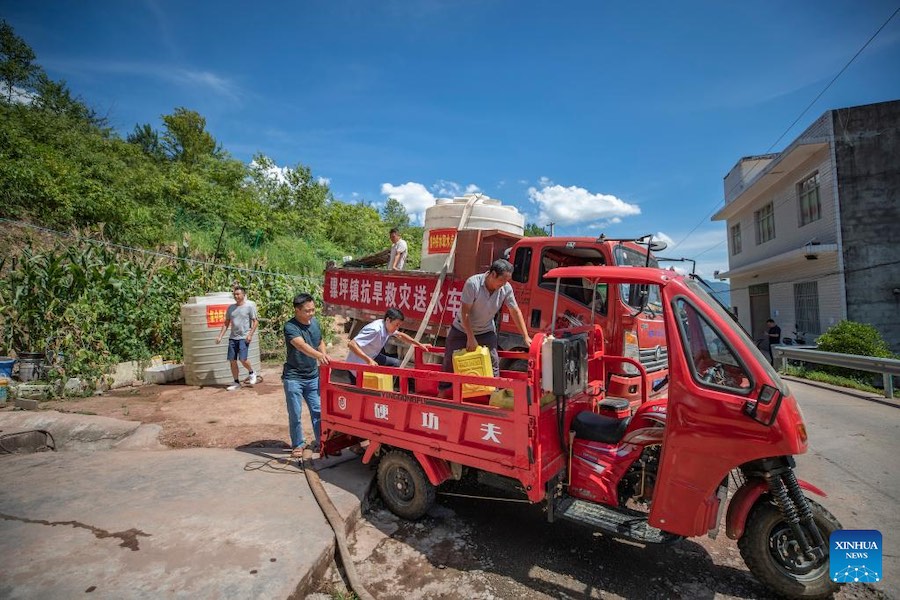 I residenti del villaggio vanno a prendere l'acqua da un punto di distribuzione nel villaggio di Luoping della contea di Wushan, Chongqing, nella Cina sudoccidentale. (13 agosto 2022-Xinhua/Huang Wei)