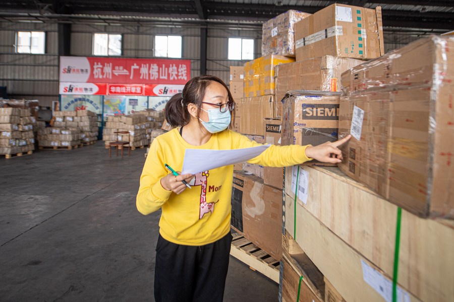 Un membro del personale controlla i pacchi presso il magazzino di una società di logistica presso il porto dell'autostrada Transfar di Hangzhou, nella provincia dello Zhejiang, nella Cina orientale. (13 aprile 2022 - Xinhua/Jiang Han)
