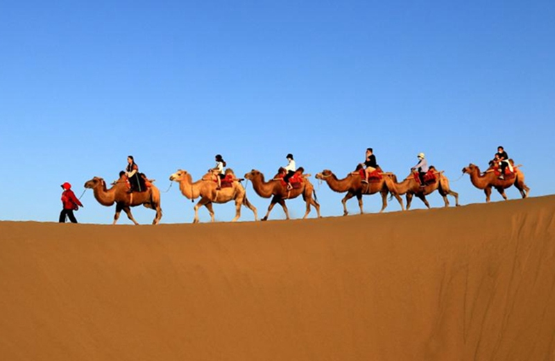 Turisti cavalcano cammelli durante le vacanze del Festival di Metà Autunno presso il monte Mingsha e la zona panoramica della Crescent Spring nella città di Dunhuang, nella provincia del Gansu, Cina nord-occidentale. (10 settembre 2022 - Zhang Xiaoliang/Xinhua)