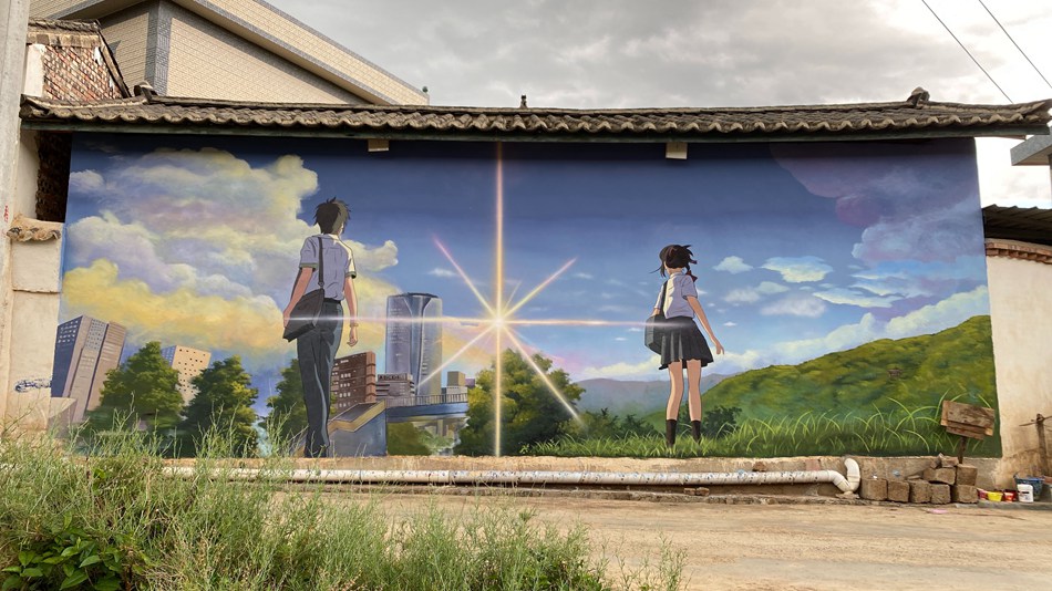 Giovane artista decora le pareti di un villaggio dello Yunnan con vivaci dipinti
