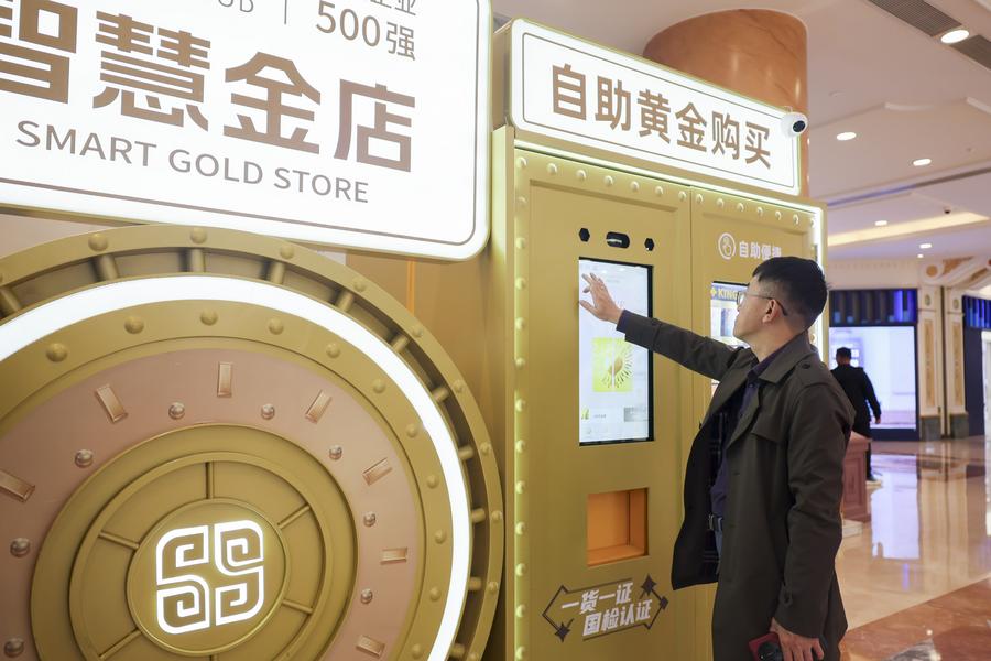 Un cittadino osserva un "negozio intelligente dell'oro" in un centro commerciale di Shanghai, nella Cina orientale. (5 maggio 2025 – Xinhua/Wang Xiang)