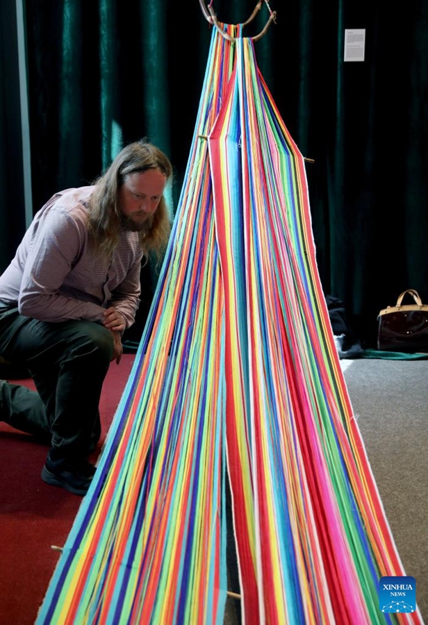David Francis osserva la coperta tradizionale Dulong all'inaugurazione del Padiglione Nazionale Cinese presso la London Craft Week 2025. (12 maggio 2025 - Xinhua/Li Ying)