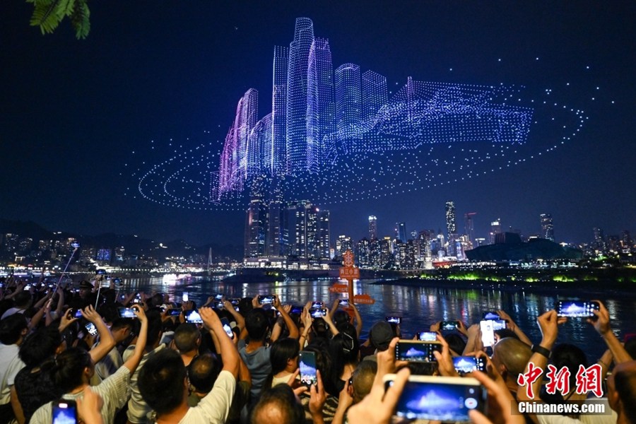 Cittadini di Chongqing assistono allo spettacolo di droni luminosi al molo di Danzishi nel distretto Nan'an della città. (17 giugno 2025 – Chinanews/He Penglei)