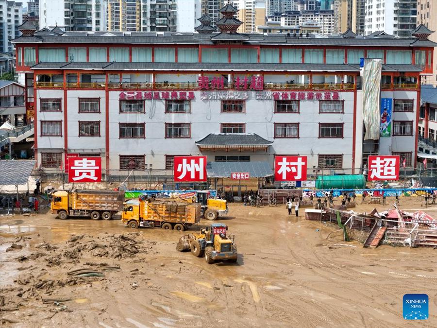 Persone ripuliscono il fango da un campo da calcio dello stadio Cun Chao nella contea di Rongjiang, provincia sud-occidentale cinese del Guizhou. (25 giugno 2025 - Xinhua/Long Jianrui)