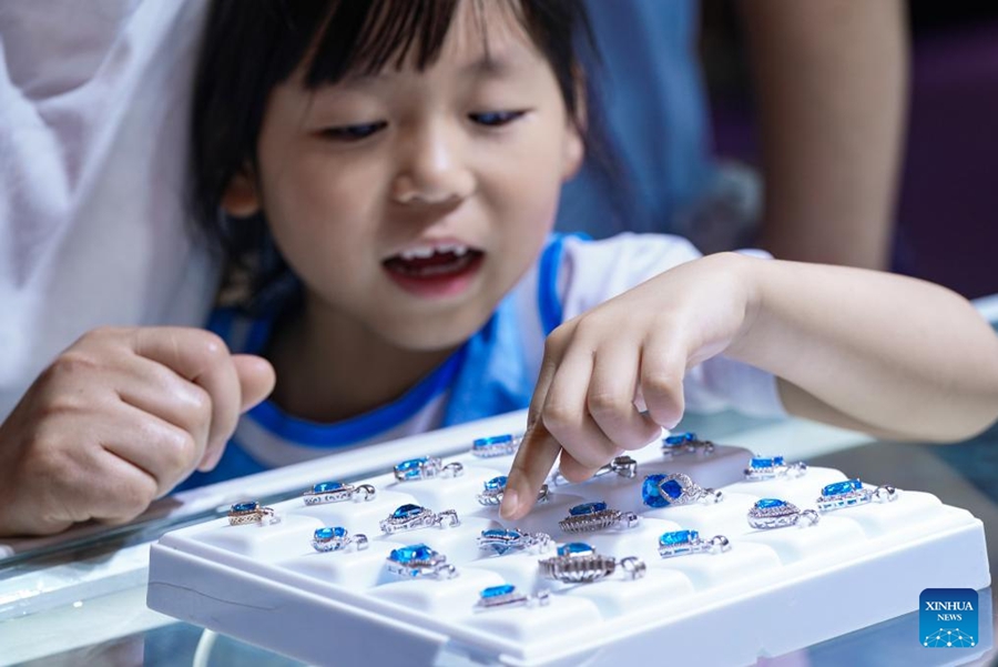 Una bambina seleziona gioielli di giada per i suoi genitori alla 2025 China Kunming International Stone Expo a Kunming, nella provincia dello Yunnan, nel sud-ovest della Cina. (10 luglio 2025 - Xinhua/Chen Xinbo)