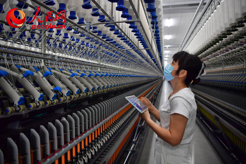 Operai monitorano il funzionamento dei macchinari nel reparto di filatura intelligente della Jiangxi Weimian Textile Group Co., Ltd. (Shi Yu/Quotidiano del Popolo Online)