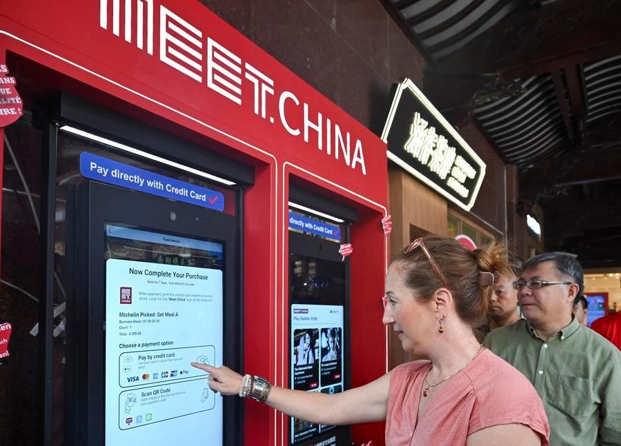 Visitatrice straniera utilizza lo schermo digitale "Meet China" dedicato ai consumi turistici inbound presso il Giardino Yuyuan a Shanghai, nella Cina orientale. (27 settembre 2025 - Xinhua/Chen Haoming)