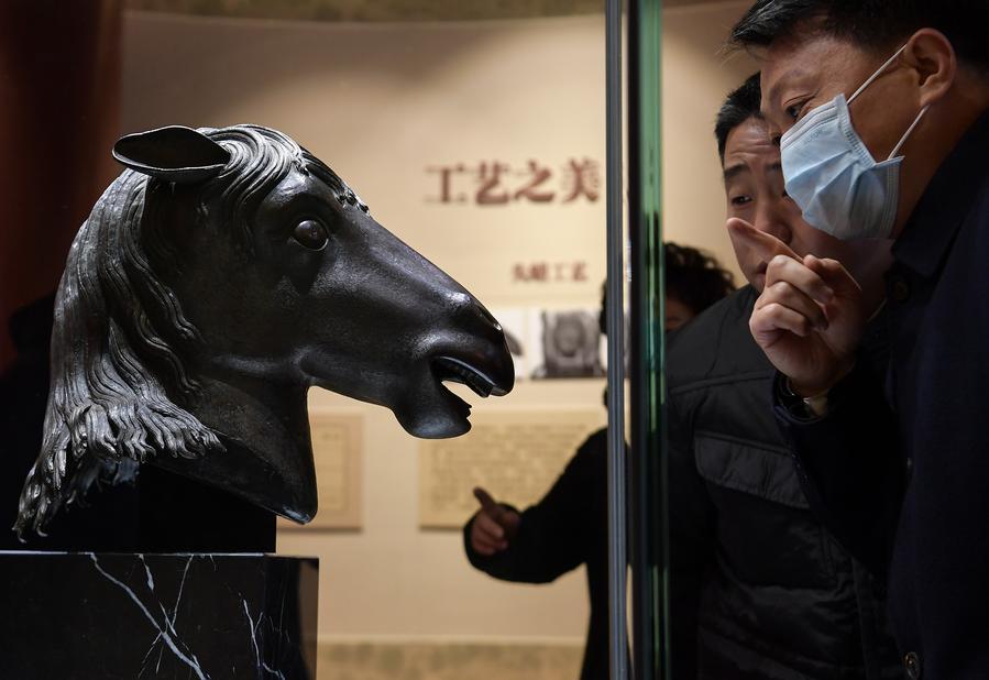 Visitatori osservano una scultura in bronzo raffigurante una testa di cavallo, sottratta in passato dallo Yuanmingyuan e attualmente esposta presso il Padiglione Wenshu del Tempio Zhengjue, all'interno dello Yuanmingyuan, a Beijing, capitale della Cina. (1 dicembre 2020 - Xinhua/Li He)